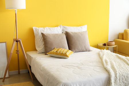 Comfortable bed and floor lamp near color wallの写真素材