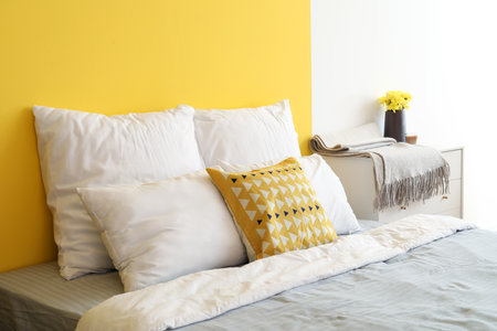 Soft pillows on big bed near color wallの写真素材