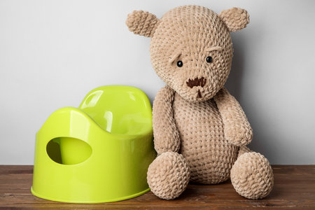 Potty and toy bear on wooden floor near light wallの写真素材