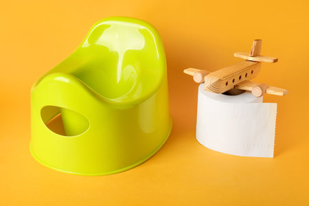 Potty, toilet paper roll and wooden plane on color backgroundの写真素材