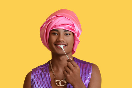 Glamorous African-American guy with chewing gum on color backgroundの写真素材