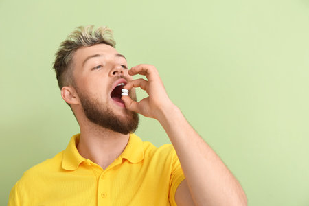 Young man chewing gum on color backgroundの写真素材