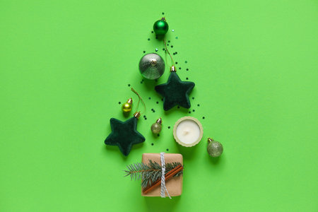 Christmas tree made of decorations, gift and candle on green backgroundの写真素材