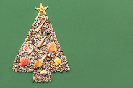 Christmas tree made of starfish, seashells and pebbles on green backgroundの写真素材