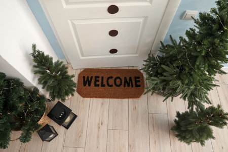 Welcome mat with Christmas trees and lanterns near white door in hallの写真素材