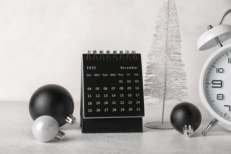 Flip calendar for December 2022 with Christmas decor and alarm clock on white backgroundの写真素材
