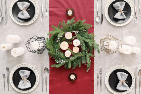Christmas table setting with wreath and candles in dining room, top view