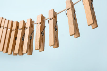 Many wooden clothespins hanging on rope against blue background, closeupの写真素材