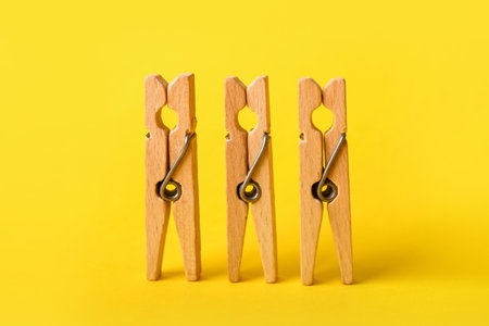 Wooden clothes pins on yellow backgroundの写真素材