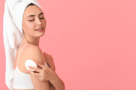 Beautiful young woman with soap on color backgroundの写真素材