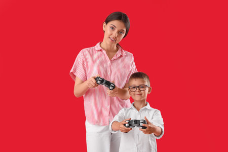 Little boy with his older sister playing video game on red background