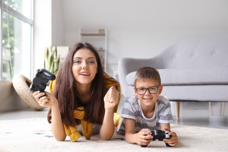 Little boy with his older sister playing video game on floor at homeの写真素材
