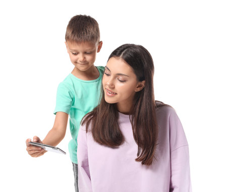 Little boy and his older sister with mobile phone taking selfie on white backgroundの写真素材