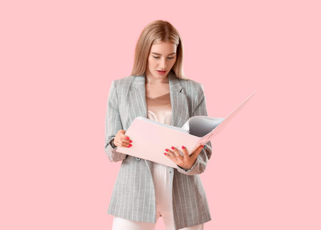 Pretty young woman with open folder on pink backgroundの写真素材