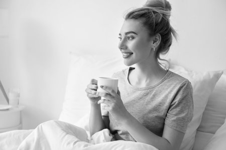 Morning of beautiful woman drinking coffee in bedの写真素材