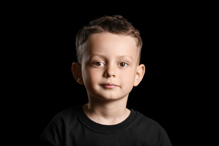 Portrait of cute little boy on dark backgroundの写真素材