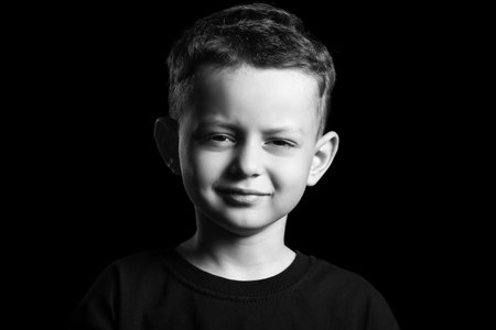 Black and white portrait of happy little boy on dark backgroundの写真素材