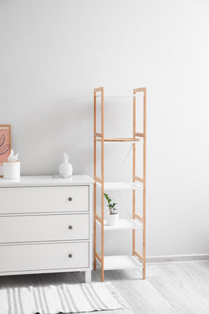 Chest of drawers with decor and shelving unit near light wall