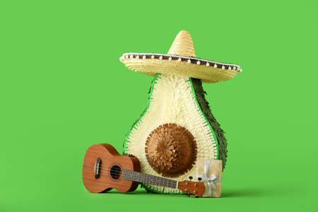 Mexican pinata in shape of avocado with sombrero hat, guitar and gift on color background