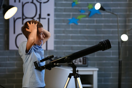 Shocked little boy with telescope looking at stars in the eveningの写真素材
