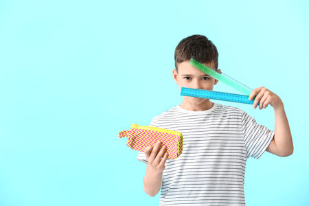 Little boy with pencil case and rulers on color backgroundの写真素材