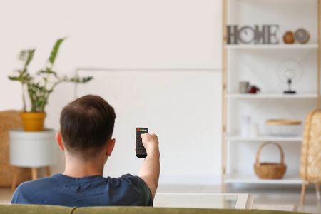 Man watching TV on sofa at homeの写真素材