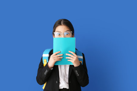 Cute Asian school girl on color background