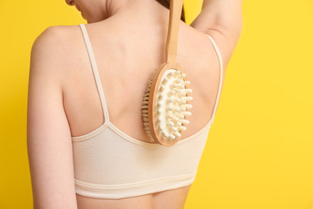 Beautiful young woman with massage brush on color backgroundの写真素材