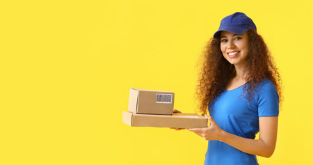 Female African-American courier with parcels on color backgroundの写真素材