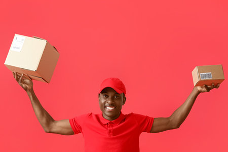 African-American delivery man with parcels on color backgroundの写真素材