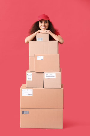 Female African-American courier with many parcels on color backgroundの写真素材