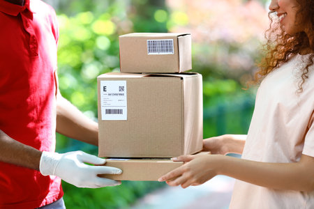 African-American woman receiving parcel from delivery man outdoorsの写真素材