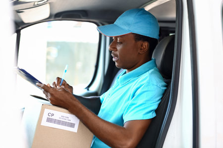 African-American courier of delivery company sitting in carの写真素材