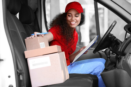 African-American courier of delivery company sitting in carの写真素材