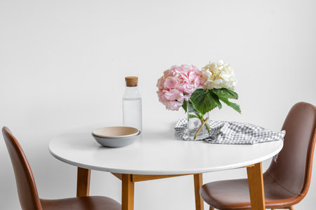 Vase with hydrangea flowers on dining table near light wallの写真素材