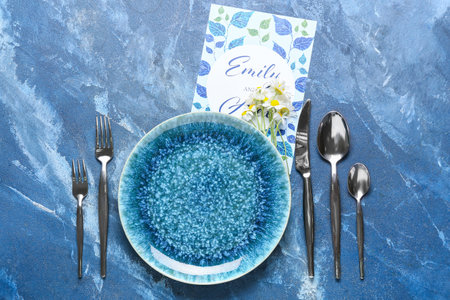 Beautiful table setting with wedding invitation and chamomile flowers on color background