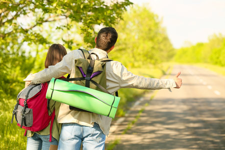 Young couple with backpacks hitchhiking on the roadの写真素材
