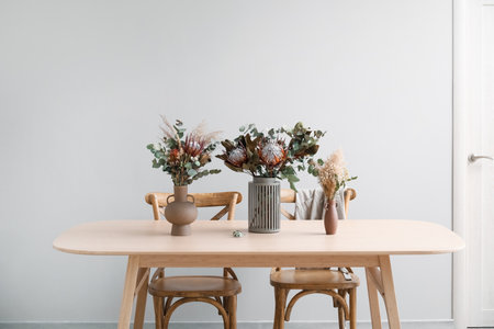 Vases with dried flowers on dining table in room