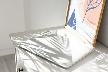 Modern laptop on table near light wallの写真素材