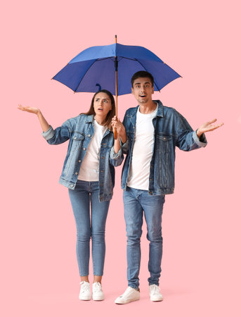 Young couple with umbrella on color backgroundの写真素材