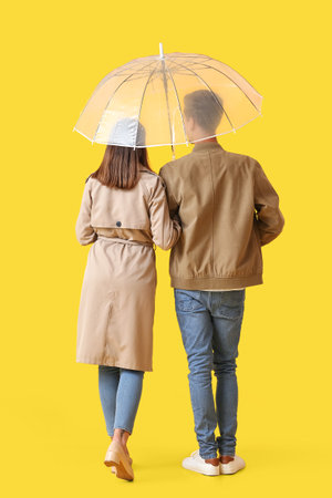 Young couple with umbrella on color backgroundの写真素材