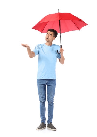 Displeased young man with umbrella on white backgroundの写真素材
