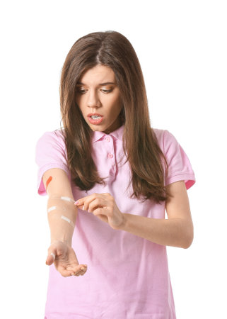 Young woman removing medical patch against white backgroundの写真素材