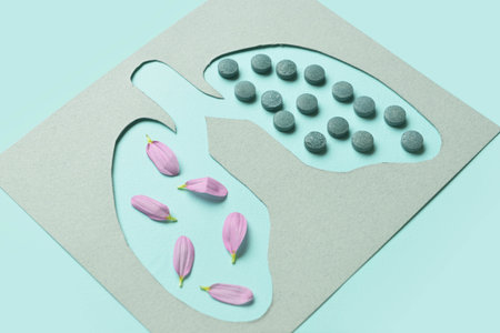 Paper lungs with flower petals and pills on blue backgroundの写真素材