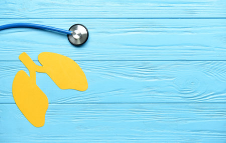 Yellow paper lungs with stethoscope on blue wooden backgroundの写真素材