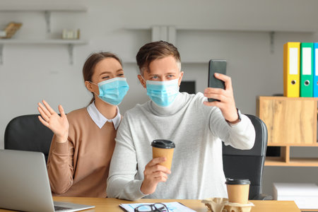 Colleagues in medical masks taking selfie in office