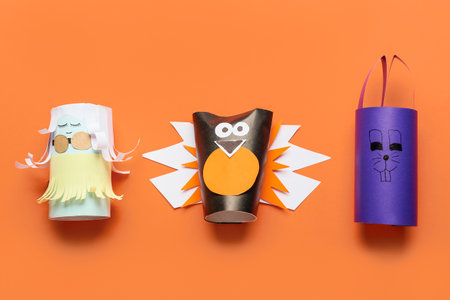 Doll, bird and rabbit made of cardboard tubes for toilet paper on orange backgroundの写真素材