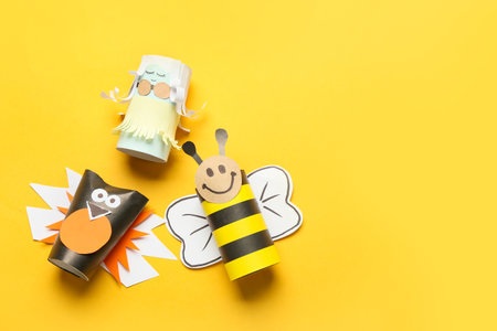 Doll, bird and bee made of cardboard tubes for toilet paper on yellow backgroundの写真素材