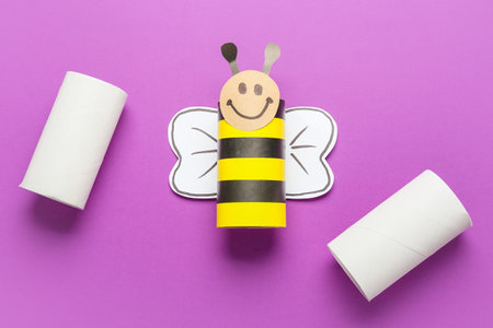 Bee made of cardboard and tubes for toilet paper on purple backgroundの写真素材