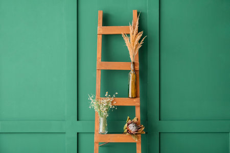 Vases with different dried flowers on ladder near color wallの写真素材